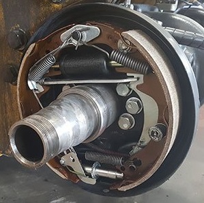Forklift wheel with its brake drum open, showing the brake shoes, wheel cylinder and other brake components all assembled together